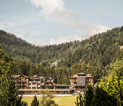 Hotelgebäude eingebettet in grüne Berge und Wald unter blauem Himmel