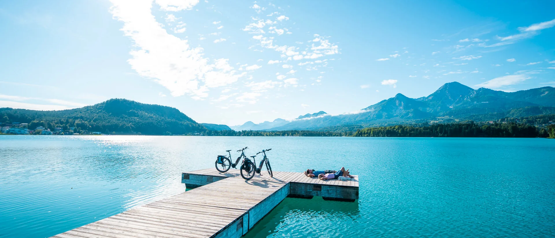 Marken © Kärnten Werbung - Gert Perauer Menschen entspannen auf Steg mit Fahrrädern an blauem See und Bergen