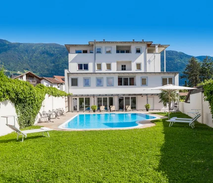 Modernes weißes Gebäude mit Schwimmbad und Bergen im Hintergrund