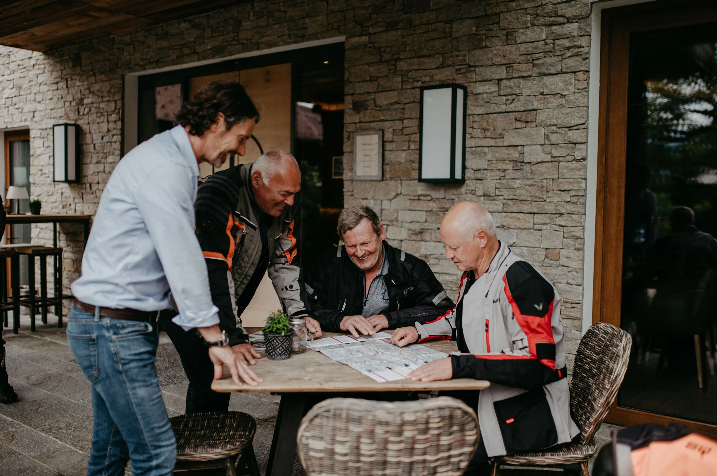 Motorradhotel © Nadia Jabli Vier Männer planen eine Reise mit einer Karte an einem Tisch draußen