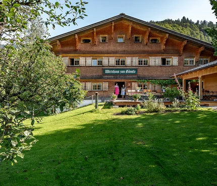 Traditionelles Gasthaus in einer grünen Landschaft mit zwei Personen an der Tür