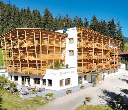 Hotel Melodia del Bosco mit Holzfassade in bergiger Waldlage