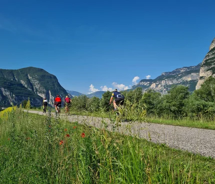Radfahrer auf einem Weg mit Bergen und blauem Himmel im Hintergrund