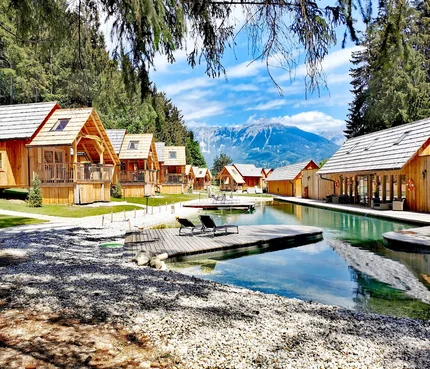 Holzhütten am See mit Bergblick und Liegestühlen auf Holzsteg