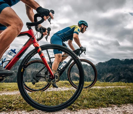 Zwei Radfahrer fahren auf einem Bergpfad bei bewölktem Himmel