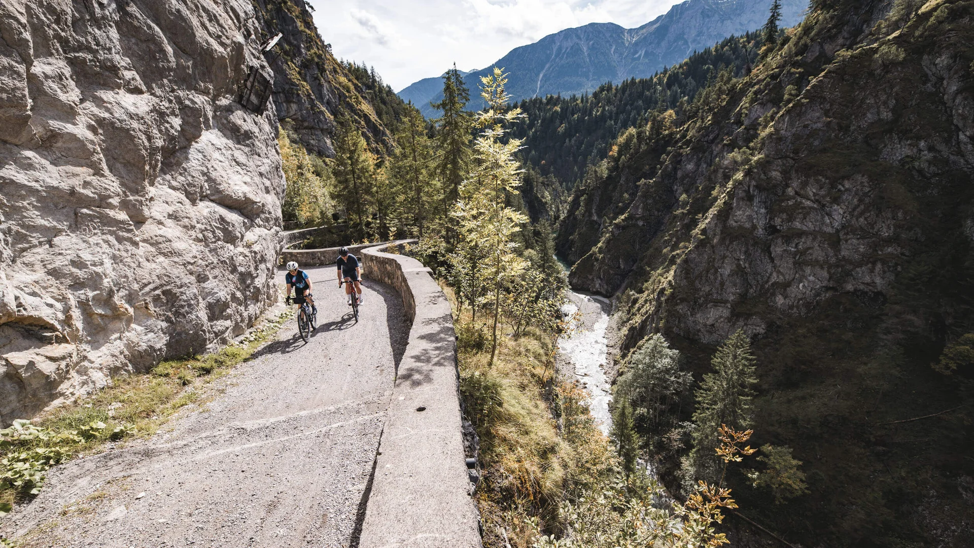 Gravelbike Holidays © Andreas Vigl Zwei Radfahrer auf Bergweg entlang Fluss in bewaldeter Schlucht