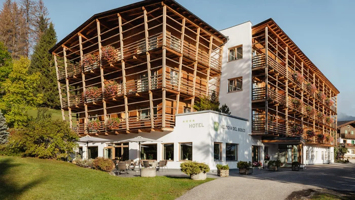 Hotel Melodia del Bosco mit Holzfassade und Blumen auf Balkonen im Grünen
