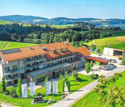 Gebäude mit rotem Dach und Solarzellen umgeben von grüner Landschaft und Hügeln