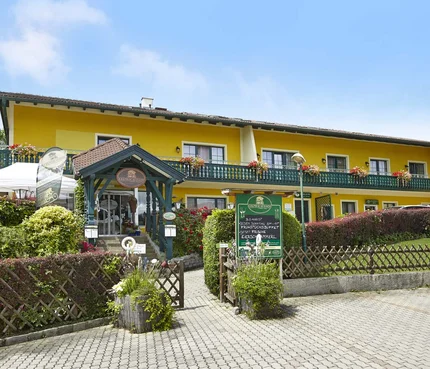Gelbes Hotel mit grünem Eingang und Blumen an der Terrasse