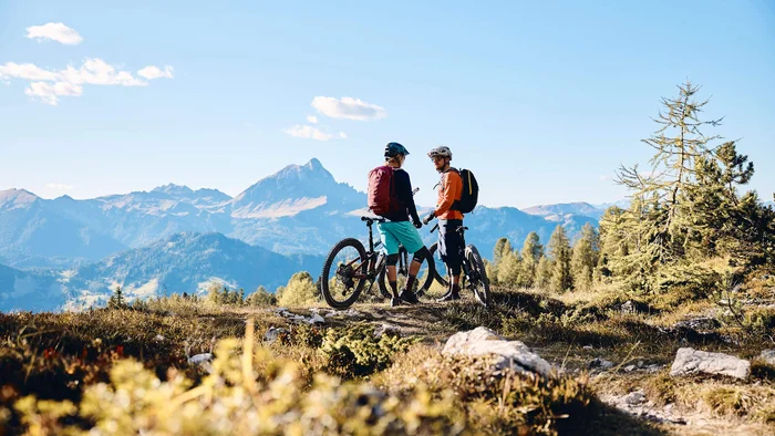 Zwei Mountainbiker stehen mit ihren Fahrrädern in den Bergen bei klarem Himmel