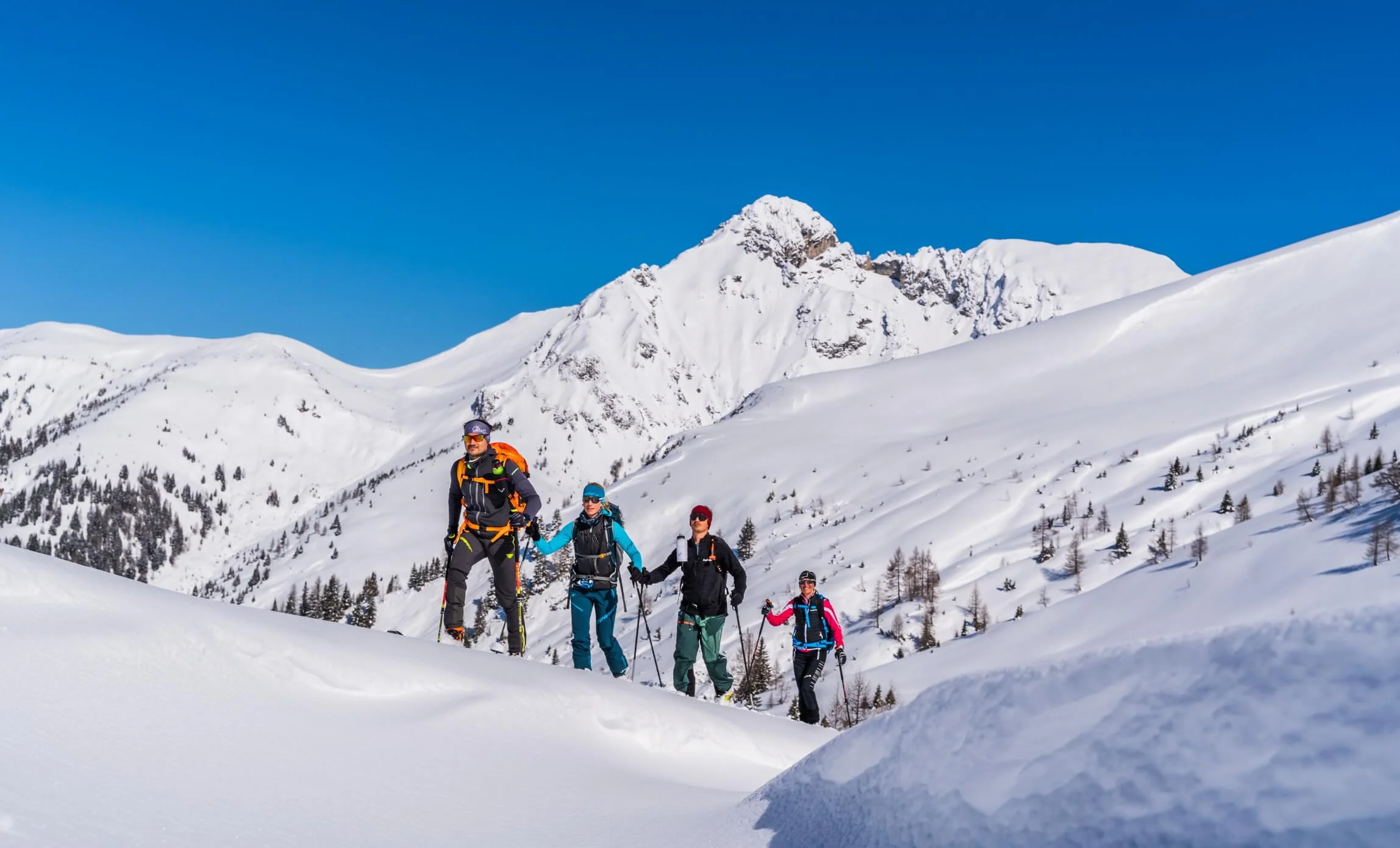Langlauf & Skitourenhotel © TVB Großarltal / Peter Maier Vier Personen beim Schneeschuhwandern in den schneebedeckten Bergen bei klarem Himmel