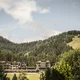 Hotelgebäude umgeben von Wäldern und Bergen unter bewölktem Himmel
