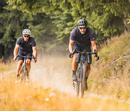 Zwei Männer fahren Mountainbikes auf einem Naturweg im Wald