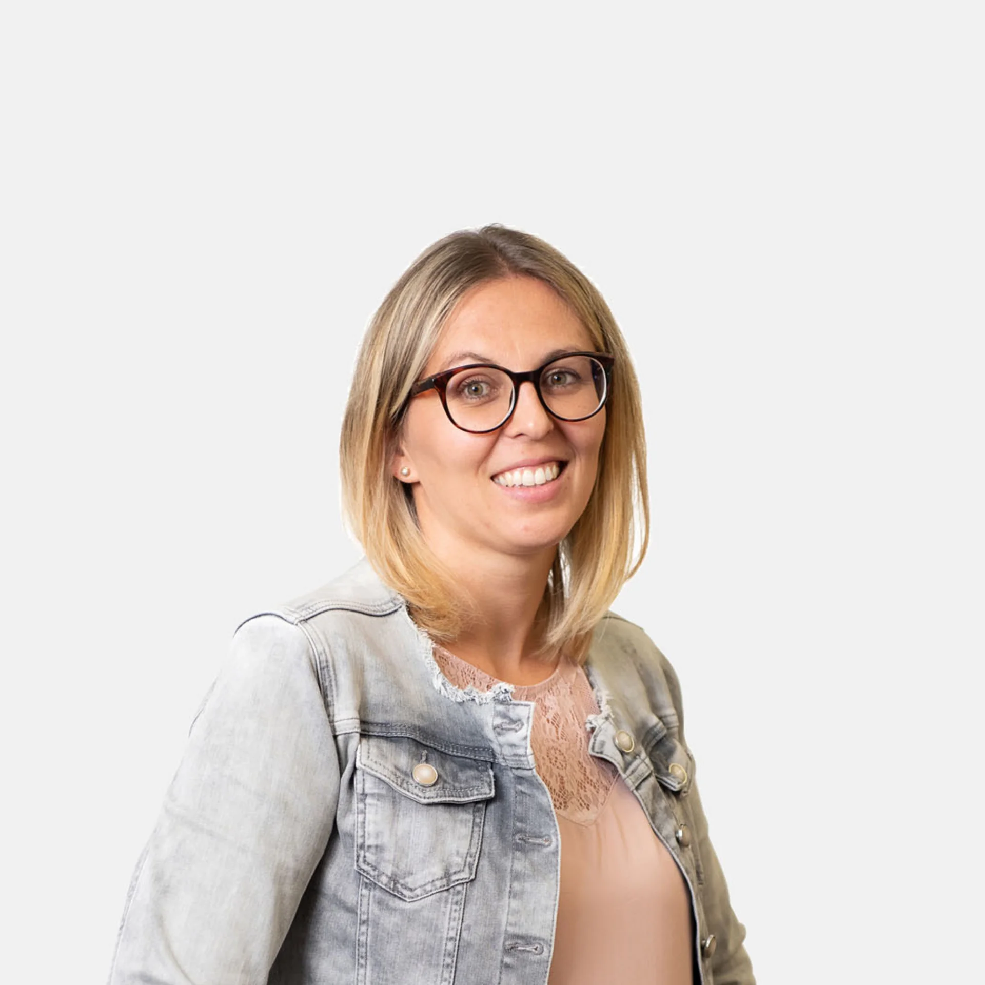 Lächelnde Frau mit Brille trägt Jeansjacke vor weißem Hintergrund