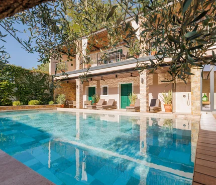 Haus mit Swimmingpool und Garten unter blauem Himmel