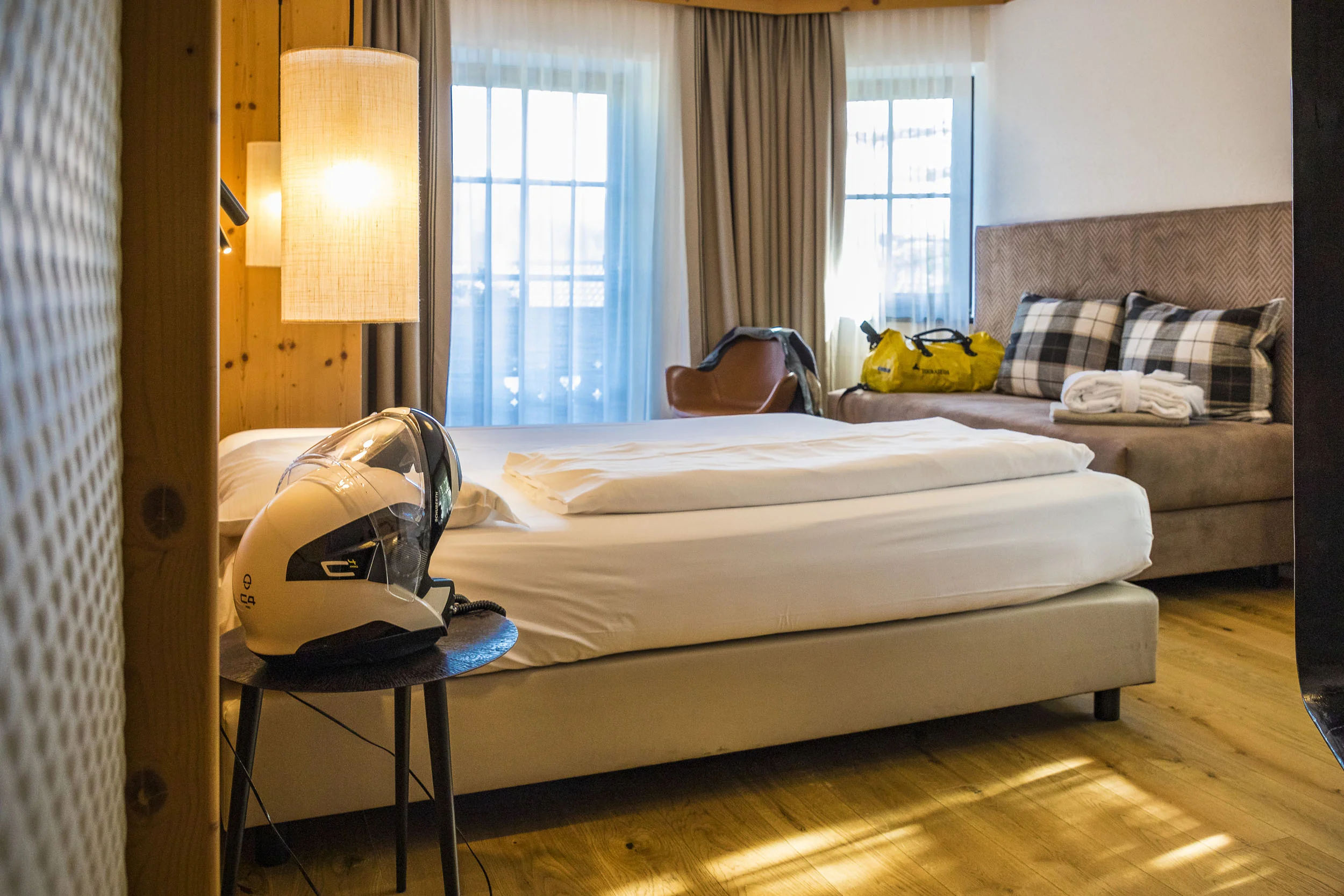 MoHo - Motorrad Hotels © Alexander Seger Gemütliches Hotelzimmer mit Einzelbett, Stuhl und Motorradhelm auf dem Nachttisch