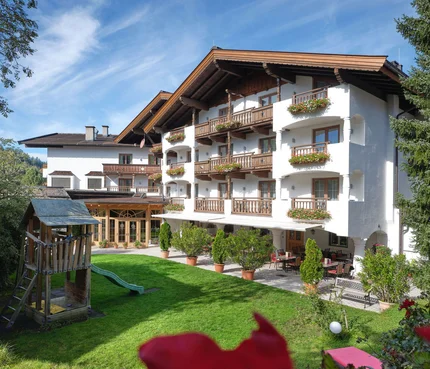 Hotelgebäude mit Balkonen und Spielplatz im Garten
