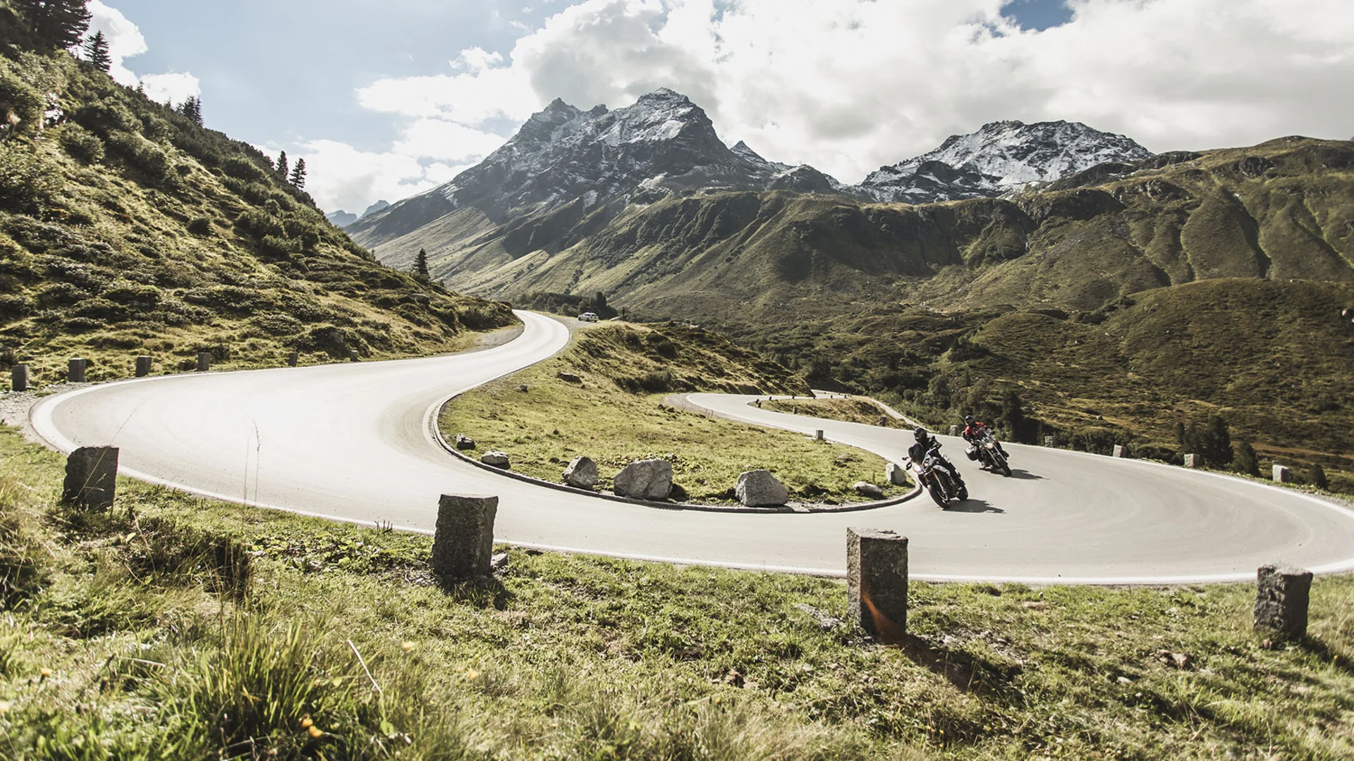 Motorradhotel © Christoph Schöch Motorradfahrer auf kurviger Bergstraße mit schneebedeckten Gipfeln