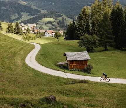 Zwei Radfahrer auf einem Weg im grünen Tal mit Bergen im Hintergrund