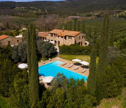 Steinhaus mit Pool umgeben von Bäumen in einer grünen Hügellandschaft
