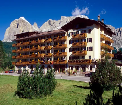Hotel Villa Argentina vor Bergen und grünem Rasen bei klarem Himmel