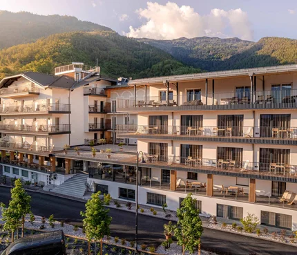 Modernes Hotelgebäude vor bewaldeten Bergen im Sonnenlicht