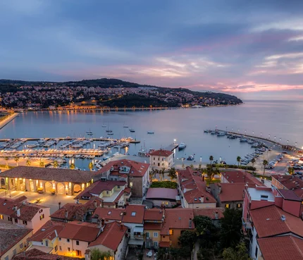 Abendlicher Blick auf Hafen und Stadt mit beleuchteten Gebäuden am Wasser