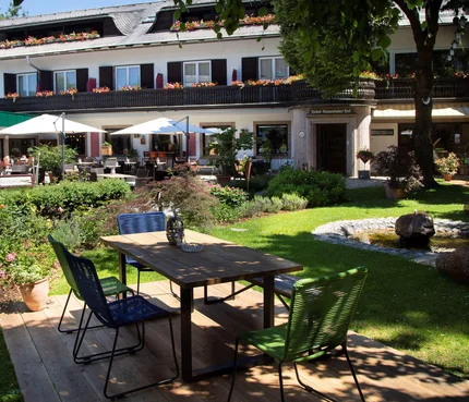 Gartenterrasse mit Tisch, Stühlen und Springbrunnen vor einem Hotel