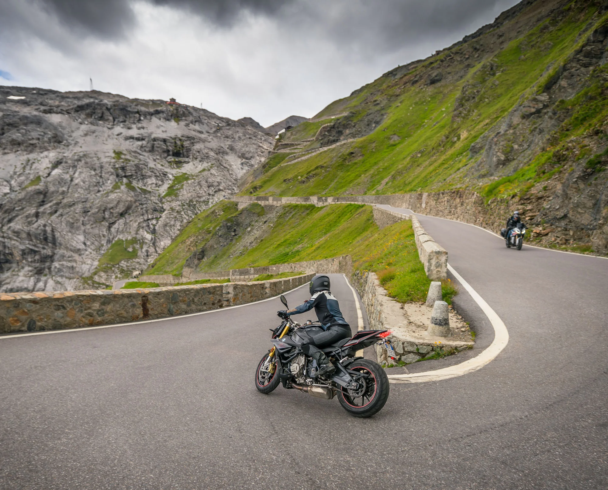 MoHo - Motorrad Hotels © Moppetfoto.de Motorradfahrer auf kurviger Bergstraße mit steilen Felswänden und Wolken