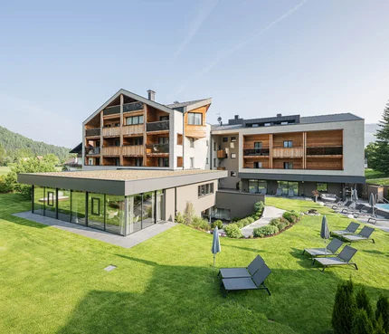 Modernes Hotel mit Garten, Pool und Sonnenliegen in sonniger Landschaft